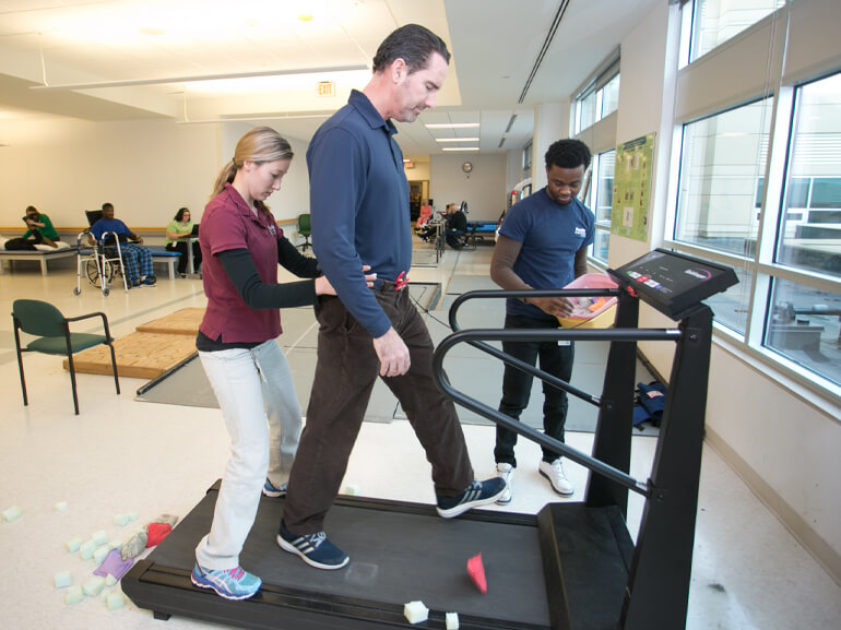 Adult male cancer patient walks on treadmill as part of cancer rehabilitation exercises