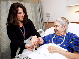 therapist assisting patient in hospital bed