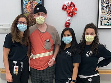 Jonathan standing with three female nurses with a mask on.