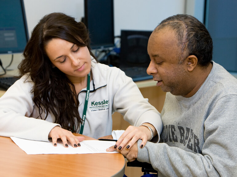  Female brain injury rehabilitation therapist works with adult male patient on reading skills