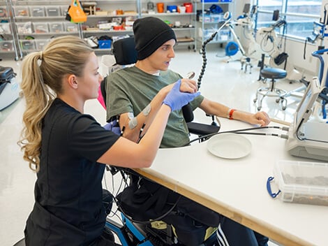 Young man with spinal cord injury works with his therapist.