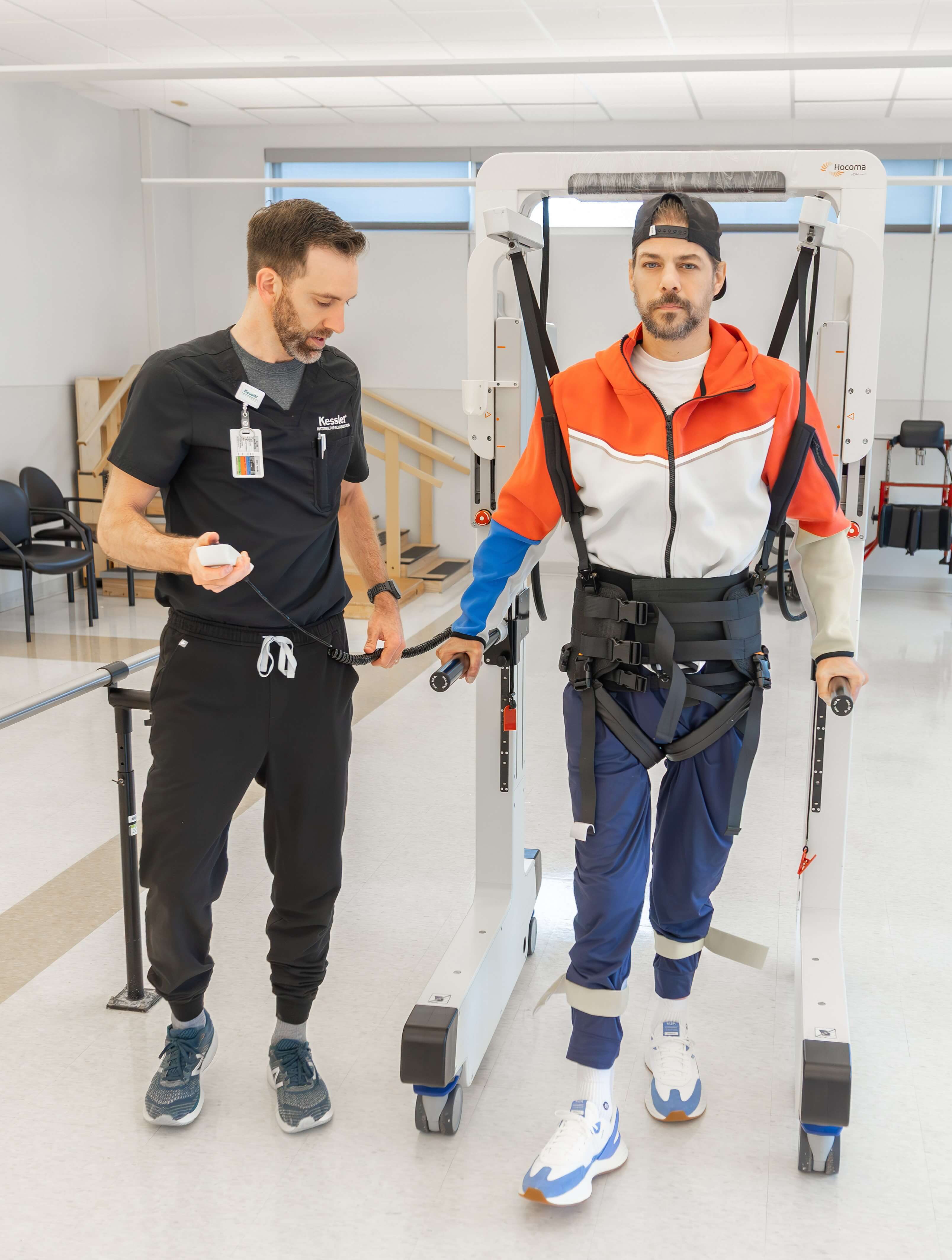 Photo of Charles Schembri and a therapist at Kessler Institute for Rehabilitation using the Andago weight support harness for gait training. 