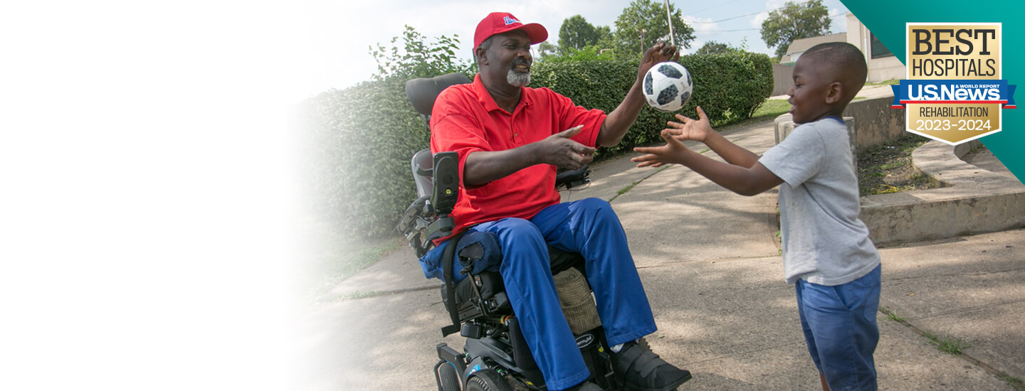 A man in a wheelchair tossing a ball with his son.