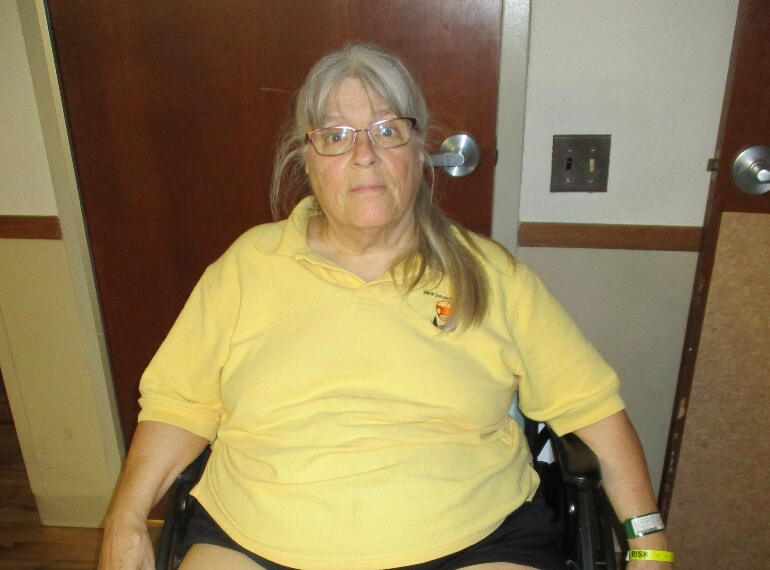 Janice sitting in a wheelchair wearing glasses