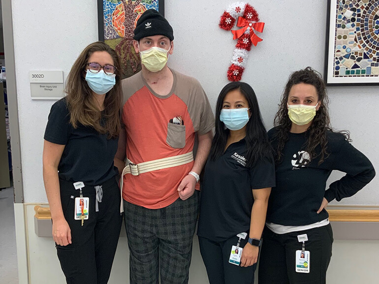 Jonathan standing with three female nurses with a mask on.