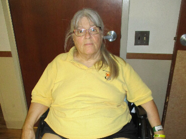 Janice sitting in a wheelchair wearing glasses