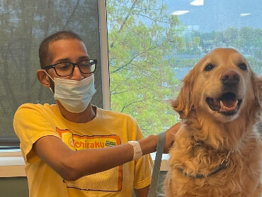 Najee sitting with a mask on while petting a therapy dog.