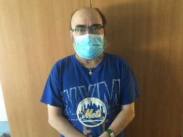 Yiotis standing in front of his hospital room door wearing a mask.