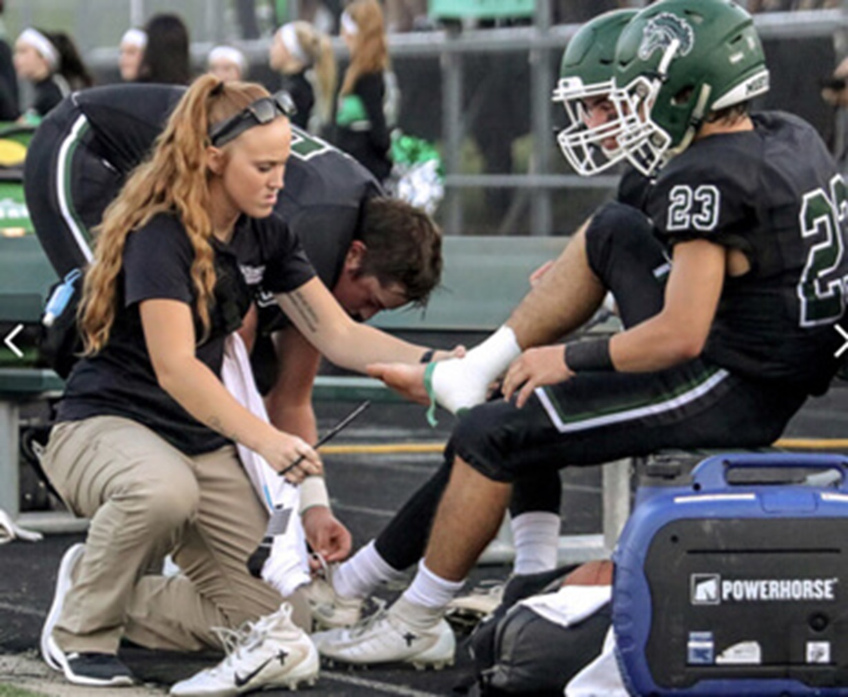 Athletic trainer assisting football player